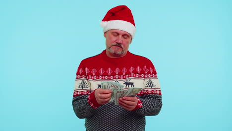 Rich-businessman-in-Christmas-sweater-holding-stack-of-money-dollar-cash-thinking-what-gift-to-buy