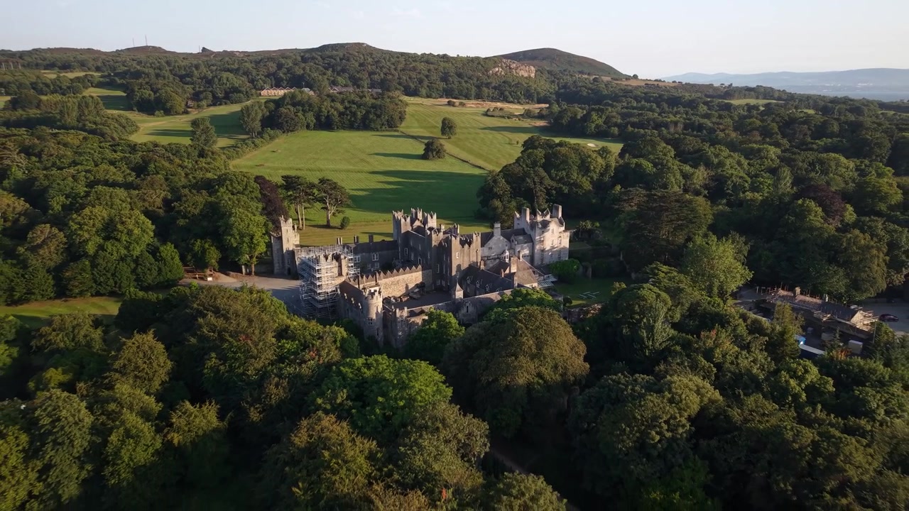 Scenic aerial reveal of Howth Castle in warm sunset light near Dublin, Ireland