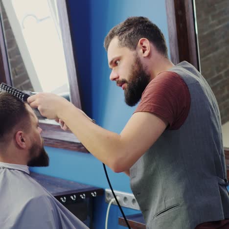 barber combing and drying hair for client