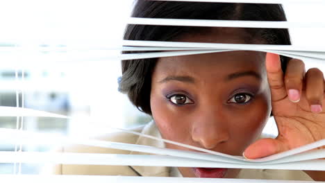 businesswoman looking through blinds