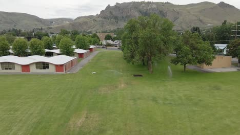 the beautiful town view surrounded with green grassland and trees in background of high mountains under the bright cloudy sky - wide shot