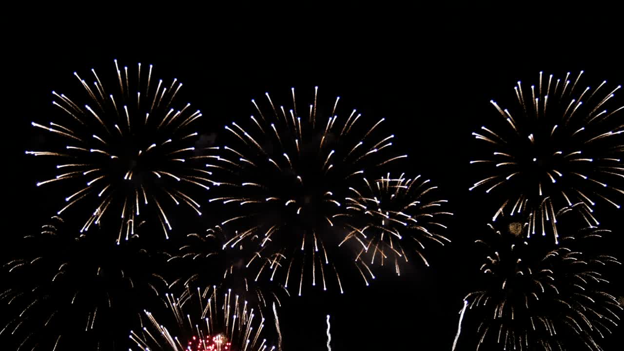 4K long shot 39s. loop seamless of real shining fireworks for celebration background. large golden glowing firework during new year's eve countdown festival in the sky display at night with colorful.