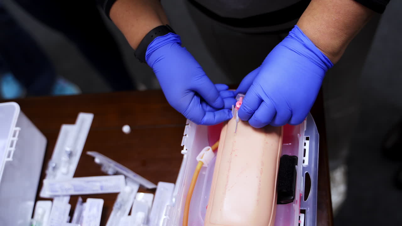 Practical procedure with an injection. Student practices to prick injection into dummy's hand in the training center. Top view. Close-up.