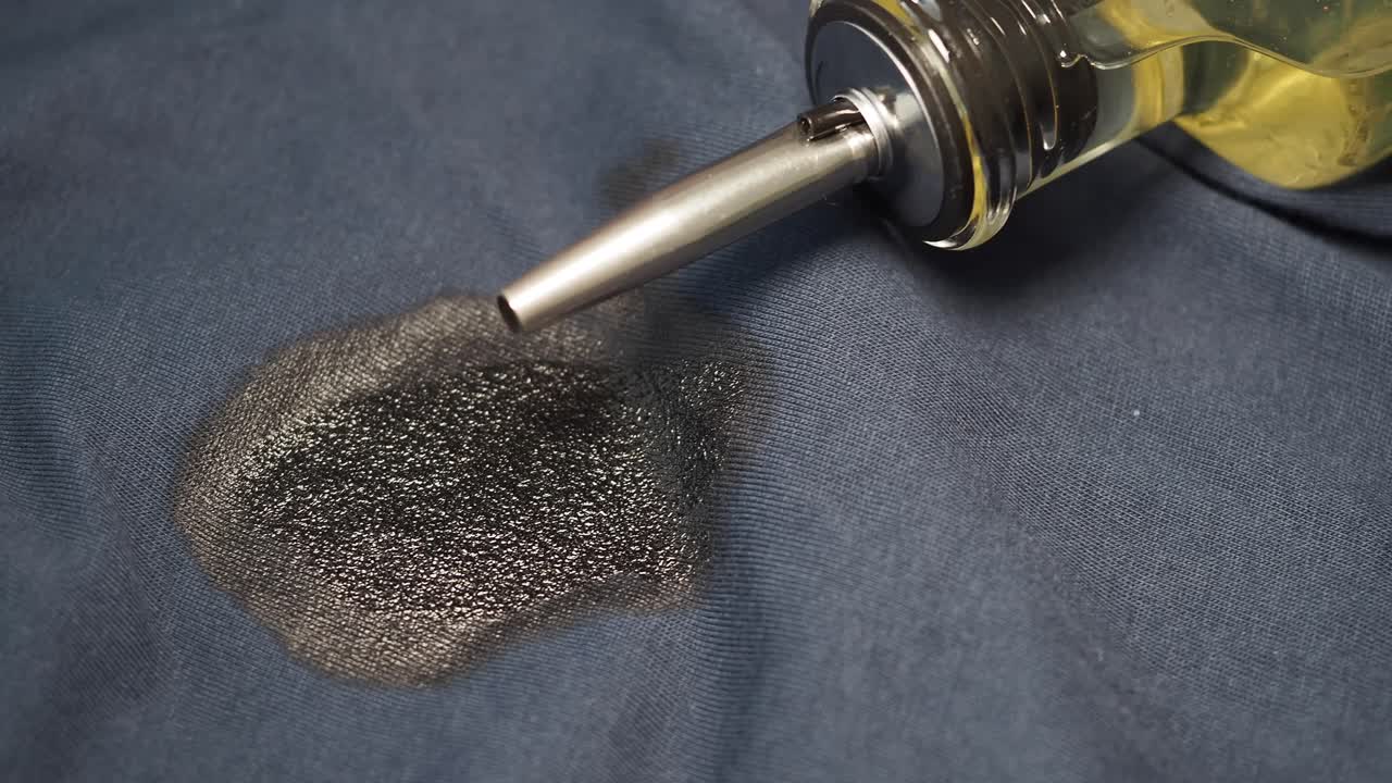 Oil being poured onto fabric, creating a stain