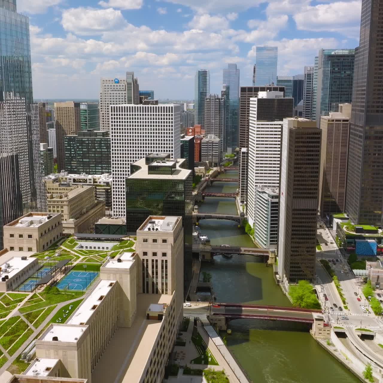 River with numerous bridges coming through the city. Drone footage among the skyscrapers of Chicago
