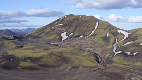 forward drone view towards a green mountain near bláhylur lake in landmannalaugar, iceland