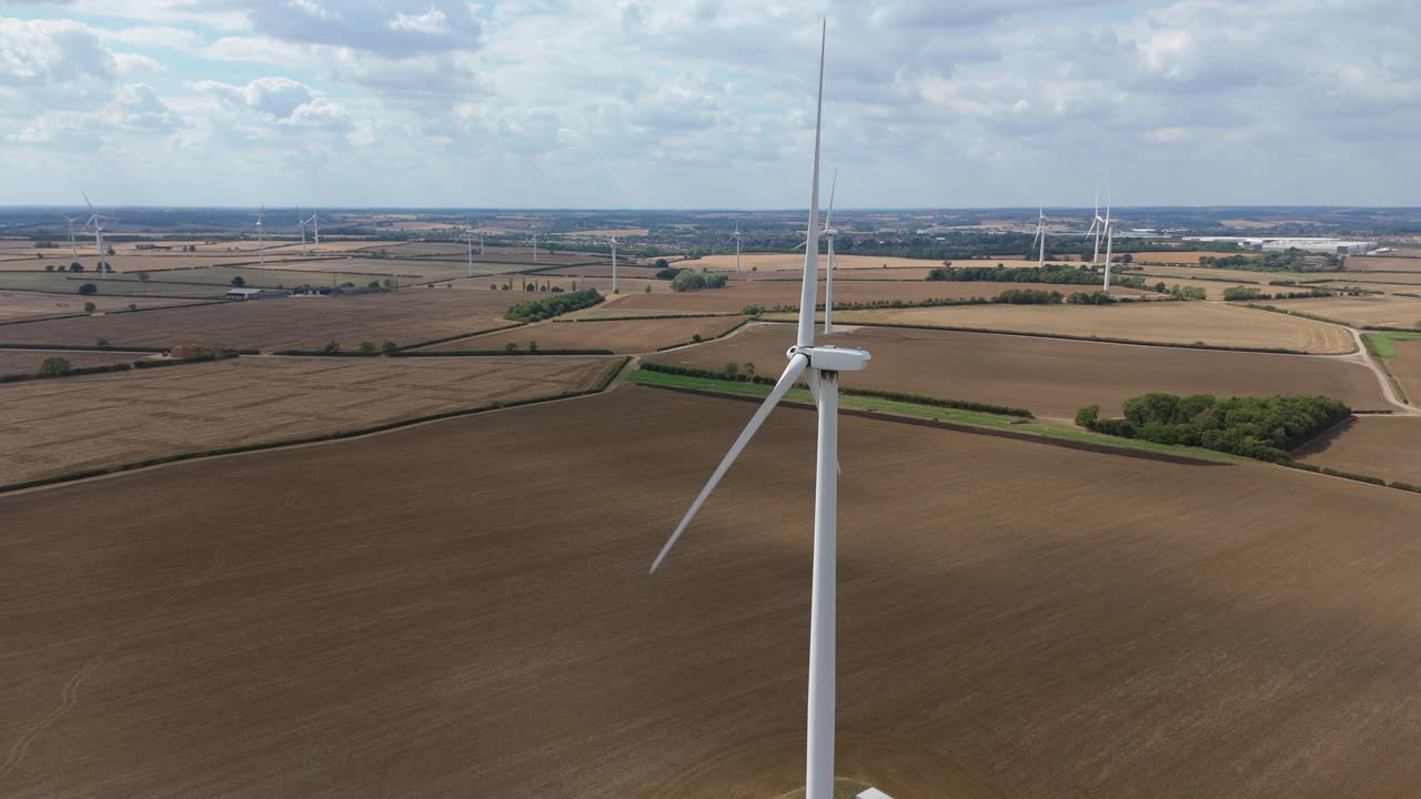Aerial drone view of wind turbines across golden fields in Burton Latimer England showing renewable energy power generation and rural electricity infrastructure