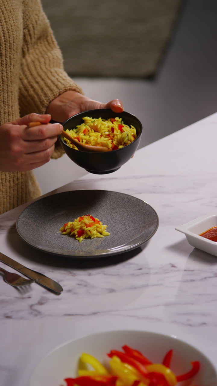 video vertical de cerca de una mujer en casa en la cocina preparando una comida vegetariana o vegana saludable de pasta de orzo y tomates asados