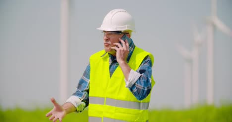 Wütender-Ingenieur,-Der-Am-Handy-Gegen-Windmühlenfarm-Spricht