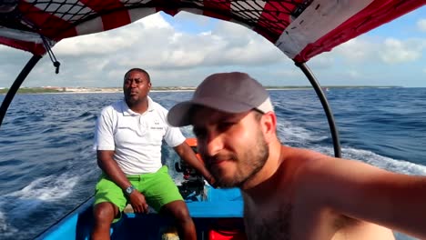 tourist man and tanzanian guide looking for dolphins in a motorized fiber boat. zanzibar