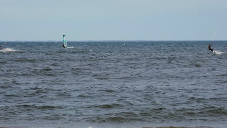 kiteboarders surfing on the deep blue sea on a sunny day - medium shot