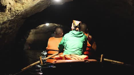 team rows through a dark, water-filled cave