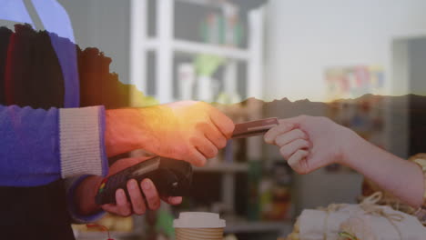 animation of an aerial view of the mountains over caucasian man paying with a credit card