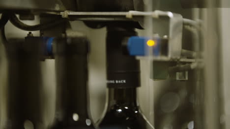 cinta transportadora de botellas de vino que pasa por un proceso automatizado de etiquetado