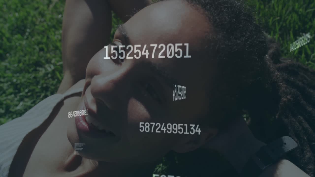 Animation of numbers processing over happy woman lying on grass