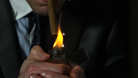 businessman lighting his cigar on black background