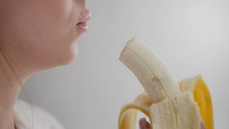 close up of lady savoring banana in bright environment with natural light highlighting details of fruit texture and hand grip while enjoying healthy snack during relaxed calm indoor moment