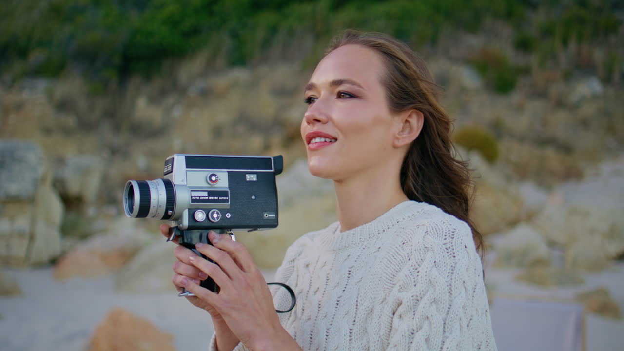Traveler shooting evening nature on retro video camera closeup. Smiling woman