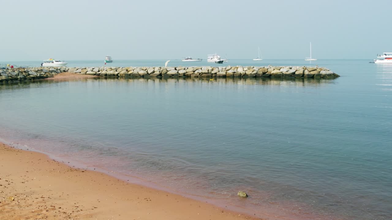 A peaceful beach scene at dawn with boats anchored highlighting the beauty of calm waters.