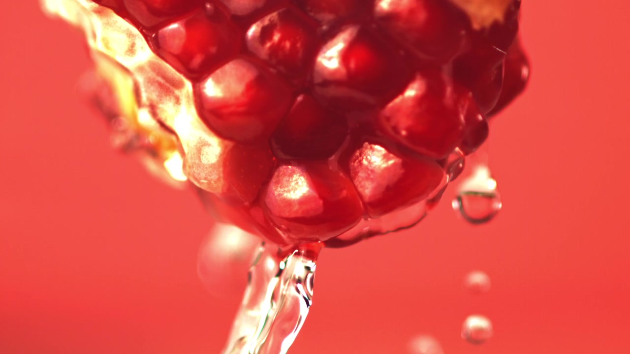 Slow Motion Water Dripping from Vibrant Red Pomegranate Seeds