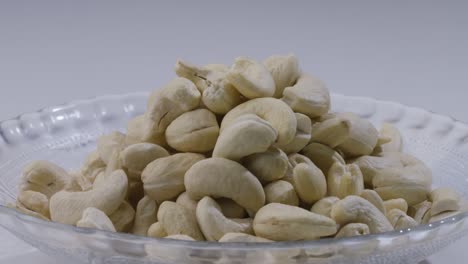 close up of hand picking up handful of cashew nuts from plate on table