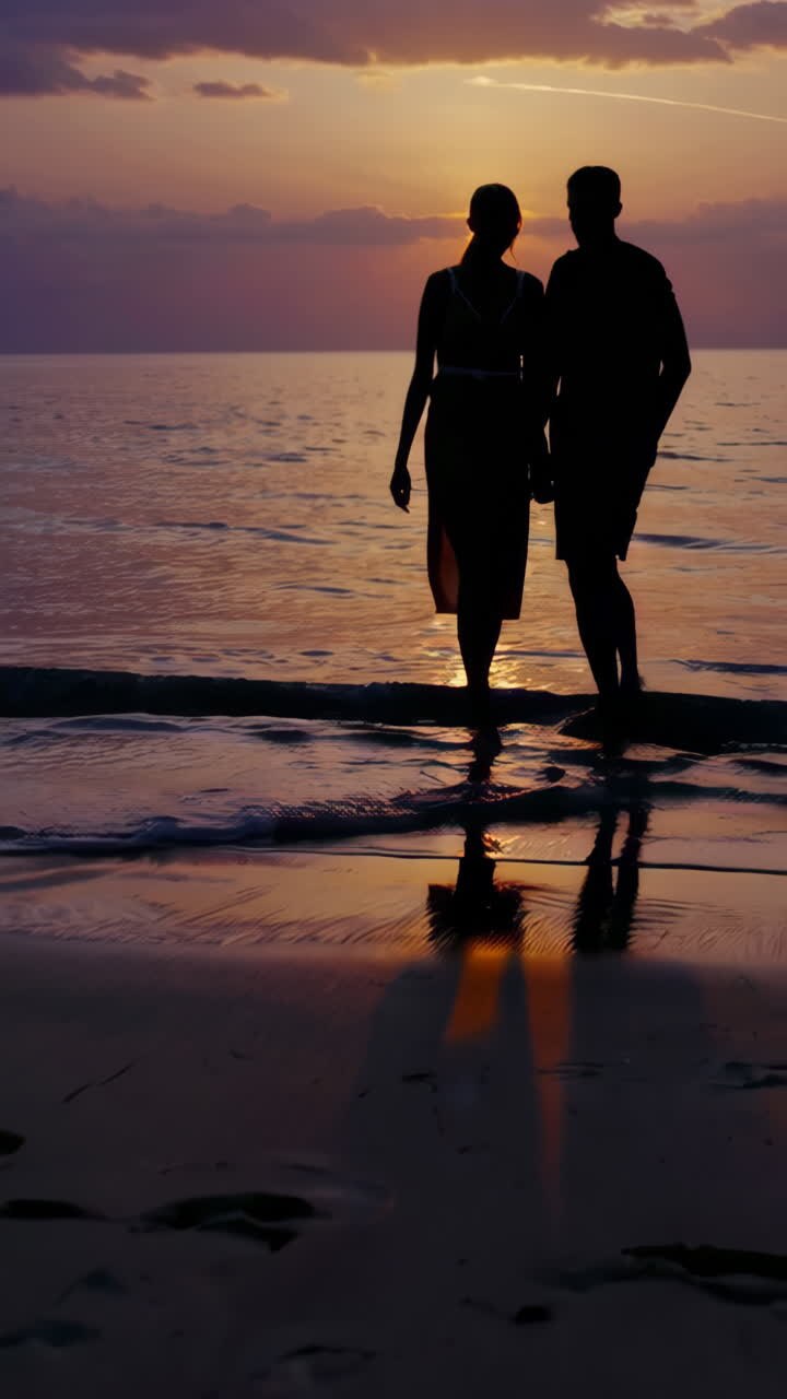 Silhouette d'un couple marchant sur une plage au coucher du soleil