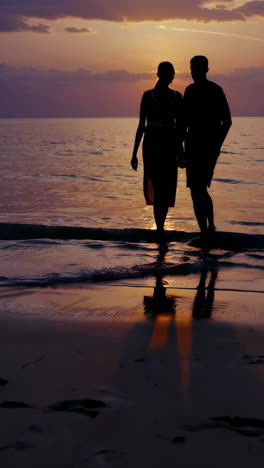 couple walking on sunset beach silhouette