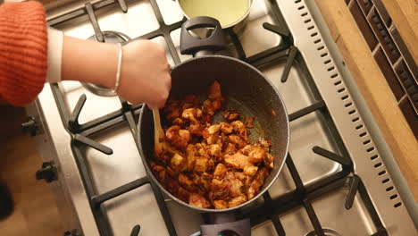 mujer cocinando pollo en una sartén