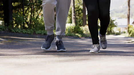 Diverse-senior-couple-running-and-holding-water-bottle-in-sunny-outdoors