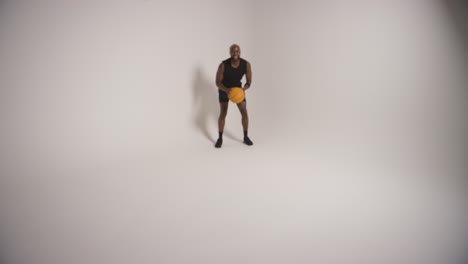 full length studio shot of male basketball player dribbling and bouncing ball against white background 3