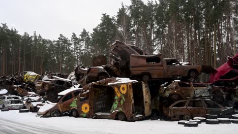 on a winter day in irpin, ukraine, a pile of burnt and destroyed cars is stacked together, with one vehicle painted with sunflower drawings, after intense battles between ukrainian and russian forces.