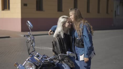 Dos-Mujeres-Jóvenes-Enamoradas-Y-Montadas-En-Motocicleta-En-La-Ciudad,-Divirtiéndose-Juntas