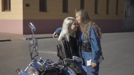 Two-young-women-in-love-and-mounted-motorcycle-in-the-city,-having-fun-together