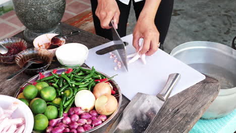 mesa de tiro en movimiento llena de ingredientes frescos, persona cortando las uñas de las patas de pollo