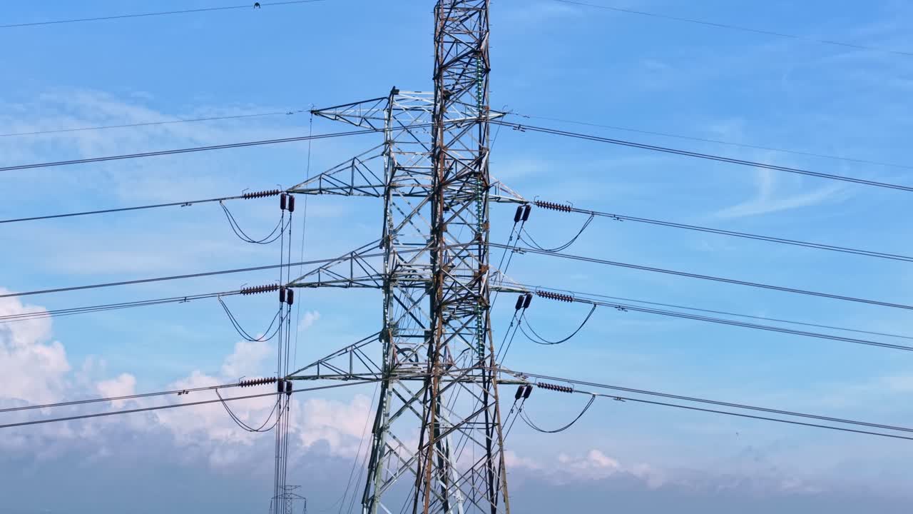 Industrial power pylons in open landscape with blue sky, illustrating electrical grid, high voltage transmission, and infrastructure concept