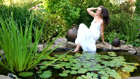 girl rests on the shore of a pond