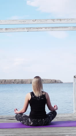 woman meditating on a dock by the lake