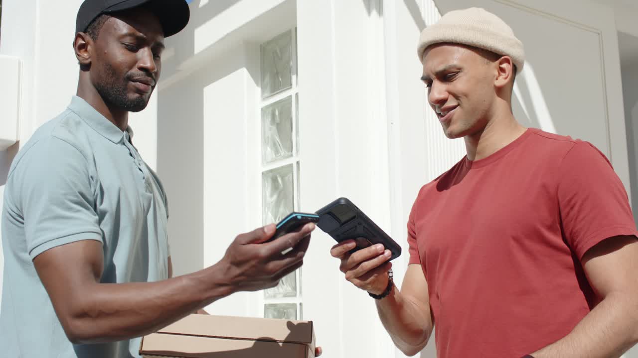 Courier and customer on payment prompt holding device tapping phone porch completing pizza handoff