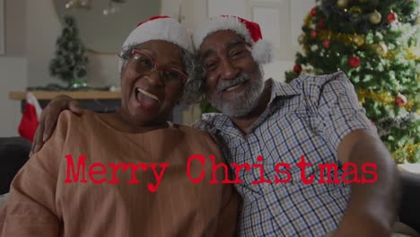 Animación-De-Texto-De-Feliz-Navidad-Sobre-Una-Pareja-Afroamericana-De-Alto-Nivel-Con-Gorros-De-Papá-Noel