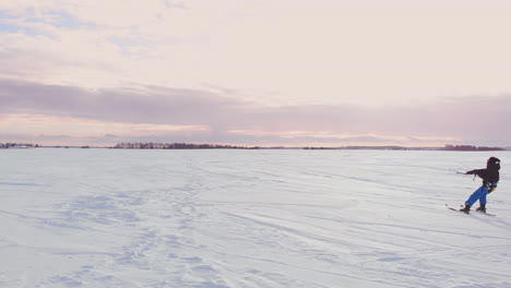 Ein-Mann-Fährt-Bei-Sonnenuntergang-Im-Schnee-Auf-Einem-Feld-Ski.-Sein-Fallschirm-Zieht.-Kitesurfen-Im-Schnee..