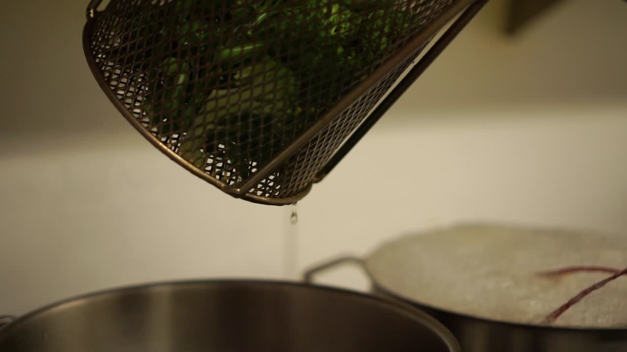 Close Up - Draining steamed green fresh broccoli and putting it on a plate
