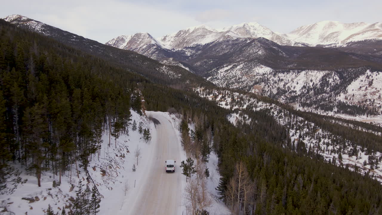 Drone Shoot Rocky Mountain Winter. Aerial shoot van driving on the snow pass road with Mummy Mountain and Bighorn Mountain in the background.. Winter snow drone of Colorado National Pack