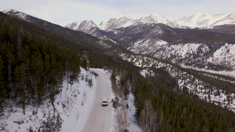 drone shoot rocky mountain winter. aerial shoot van driving on the snow pass road with mummy mountain and bighorn mountain in the background.. winter snow drone of colorado national pack
