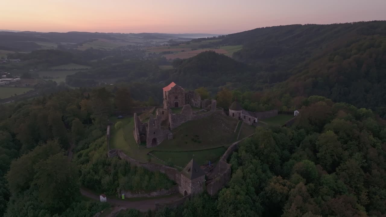 Droneperspektiv af Potstejn Slot, der hviler på en bakke ved daggry