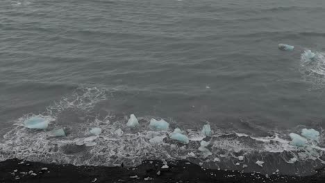 Slow-motion-panning-shot-of-waves-crashing-into-icebergs