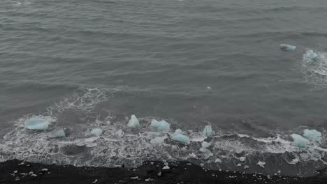 slow motion panning shot of waves crashing into icebergs