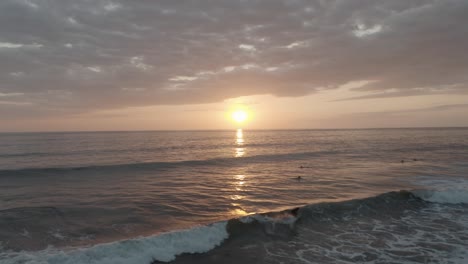 Drone,-Aerial-shot-of-surfer-catching-a-wave-during-beautiful-sunset-in-Costa-Rica,-4k