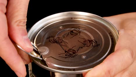 a close-up sequence shows a person’s hands opening a canned pineapple using a pull tab lid under bright, even lighting with a black background