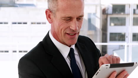 hombre de negocios usando una tableta y sonriendo a la cámara