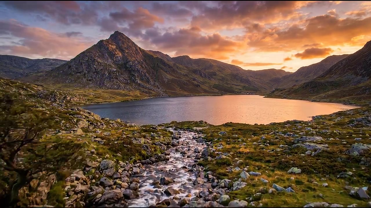 Fluss fließt durch eine felsige Berglandschaft mit herbstlich gefärbten Bäumen unter warmem Sonnenlicht.